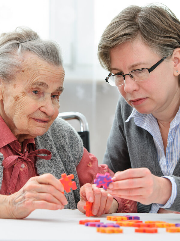 Frau puzzelt mit älterer Dame am Tisch